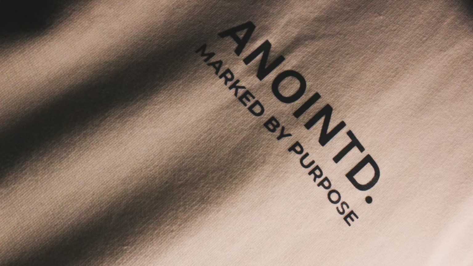 Close-up of the ANOINTD wordmark and Marked by purpose print on fabric